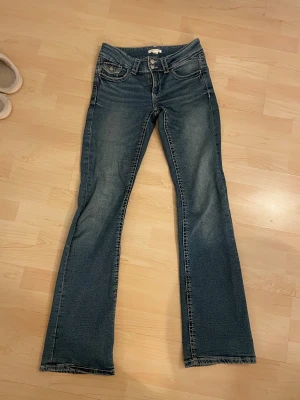 Blå bootcut jeans med låg midja - Lågmidjade bootcut jeans från Gina Young. De har dubbla knappar. Ser mörkare ut på bilden. Nästan oanvända💕Bara att skriva om frågor eller fler bilder