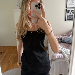 Svart linnetopp från H&M - Svart linnetopp från  H&M med glitterdetaljer. Toppen är ärmlös och har smala axelband. 