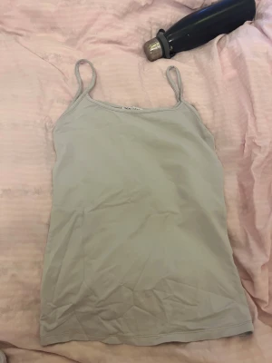 Ljusgrå linnetopp från Zara - Säljer en stilren ljusgrå linnetopp från Zara i storlek S. Toppen har tunna axelband och ärmlös design, perfekt för varma dagar. Tillverkad i mjukt och stretchigt material som sitter skönt mot kroppen. 