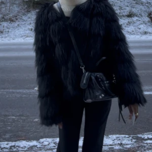 Svart pälsjacka  - Säljer en svart pälsjacka med lång, fluffig fuskpäls och oversized silhuett. Jackan har långa ärmar och ger en riktigt cool statement-look. Perfekt för dig som vill sticka ut och hålla dig varm under vintern. 