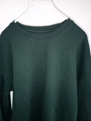 Mörkgrön sweatshirt från Jack & Jones - En enkel och stilren mörkgrön sweatshirt från Jack & Jones. Tröjan har rund hals, ribbade muddar vid ärmslut och nederkant samt lång ärm. Perfekt för chill dagar och passar till jeans eller joggers. Materialet är mjuk bomull för skön komfort.