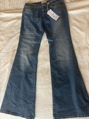 Ultra low flare jeans från Gina Tricot - Säljer dessa jeans från Gina tricot då de är snäppet för korta, helt oanvända. Snygga ljusblå jeans med ultra låg midja och riktigt utsvängda ben från Gina Tricot. Klassisk femficksmodell med rosa sömmar på bakfickorna och och även framtill. Perfekt för som gillar en vardagligt snygg stil. 