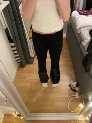 Svarta bootcut byxor i mjukt tyg - Säljer ett par svarta bootcut byxor med låg midja. De är gjorda i ett mjukt material som sitter skönt och har en snygg passform som framhäver benen. Perfekta om du gillar en stilren look med lite extra sväng i benen.