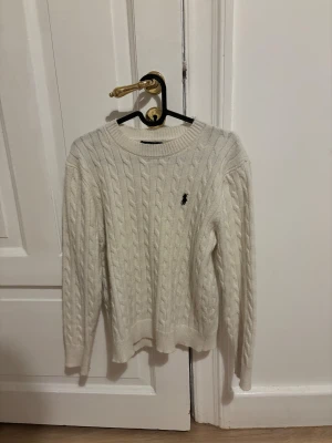 Vit kabelstickad Ralph Lauren - Säljer en vit kabelstickad tröja från Polo Ralph Lauren i storlek M, men i verkliga fallet har den krympt i tvätt och därför sitter den mer som S. Otroligt fint skick fortsatt utan fläckar eller skador.