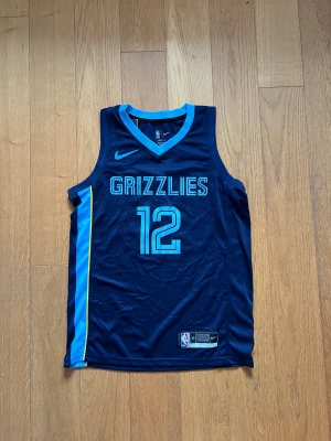 Memphis Grizzlies Ja Morant baskettröja - Snygg Memphis Grizzlies baskettröja med Ja Morant #12, officiell NBA Dri-Fit från Nike. Marinblå med ljusblå detaljer och gula inslag på sidorna. Ärmlös design i lätt och ventilerande material, perfekt för träning eller match. GRIZZLIES tryckt på bröstet och Morant på ryggen. Pris kan diskuteras! Skriv gärna om ni har frågor!