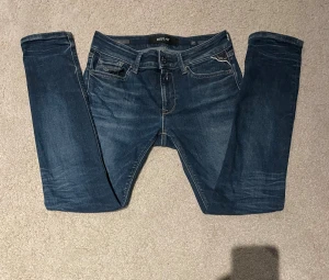 Replay Hyperflex jeans blå  - Snygga Replay Hyperflex jeans i mörkblå tvätt med slim passform. Klassisk femficksdesign, detaljerade sömmar och logotyp på fickan. Stretchigt jeansmaterial som sitter bekvämt. Perfekt för dig som gillar en modern och slimmad look.