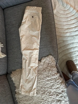 Beige chinos  W30 L32 - Säljer ett par klassiska beige chinos i storlek W30 L32. Byxorna har en rak/slim passform, bälteshällor och bakficka med knapp. Materialet är mjukt och stretchigt med 97% bomull och 3% elastan för extra komfort.