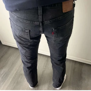 Levi's 501 mörkgrå jeans W32 L32 - Säljer ett par klassiska Levi's 501 jeans i mörkgrå tvätt. Modellen har rak passform, fem fickor och knappgylf. Jeansen är tillverkade i robust bomullsdenim och har den ikoniska läderpatchen bak i midjan samt röd Levi's-tag på bakfickan.