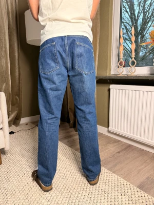 Woodbird doc cave jeans - Woodbird doc cave jeans i blå tvätt med rak passform och normal midja. Jeansen har fem fickor, synliga sömmar och Tillverkade i slitstarkt bomullsjeansmaterial, perfekta för en chill och tidlös look.