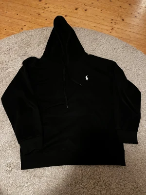 Svart hoodie från Polo Ralph Lauren - Säljer min ralph lauren hoodie i storlek S. Den är i 10/10 sick inte en ända liten skada på den finns. Det är en mycket skön hoodie som passar till allt. Mitt pris är 849kr men går att diskutera så kom med bud😁