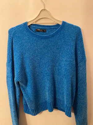 Blå ribbad stickad tröja FB Sister - Snygg blå stickad tröja från FB Sister i storlek M. Tröjan har ett ribbat mönster och är långärmad med rund halsringning. Materialet är mjukt och ger en skön känsla, perfekt för kyliga dagar. Passformen är normal och färgen är klar blå.