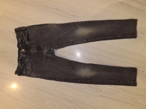 Svarta skinny jeans från Denim, stl 134 - Säljer ett par svarta skinny fit jeans från Denim i storlek 134. Jeansen har klassisk femficksdesign, resår i midjan och snygga slitningar framtill. Perfekta för dig som gillar en smal siluett och vill ha ett par bekväma jeans till vardags.