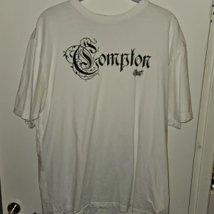 BSAT Compton T-shirt - Skön t-shirt av dansk designer BSAT. Väldigt oversized, benväm och perfekt att sova i, eller ha på sig dagligen om man gillar baggy outfits. "Compton" tryck över bröstet. Köpt 2023 och inte använd sen dess, knappt använd alls då jag bytte stil väldigt kort efter jag köpte den. 