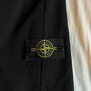 Svarta mjukisshorts från Stone Island - Svarta mjukisshorts från Stone Island med klassisk logotyp-patch på benet. Shortsen har elastisk midja med snörning och är tillverkade i mjuk bomull. Perfekta för chill eller streetwear, med snygg och enkel design.