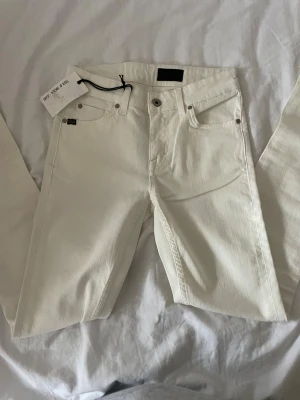 Vita jeans från Tiger of Sweden - Snygga vita jeans från Tiger of Sweden med klassisk femficksdesign och stilren patch med T/J på bakfickan. Jeansen har raka ben och normal passform, tillverkade i mjukt bomullstyg. Perfekt för dig som gillar minimalistisk och clean stil.