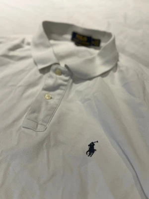 Vit Ralph Lauren Piké - Vit Ralph Lauren Piké i top top skick. Har endast använts vid få antal gånger men känner att jag inte har användning för den längre. Passar perfekt till dig som vill förnya garderoben nu inför jul!🤩 Storlek M.