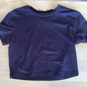 Mörkblå croppad t-shirt/ niebieska koszulka - Snygg mörkblå croppad t-shirt från SHEIN i storlek XS. T-shirten har rund hals, korta ärmar och är gjord i mjuk polyester med lite stretch för skön passform. Perfekt för dig som gillar enkel och stilren look.