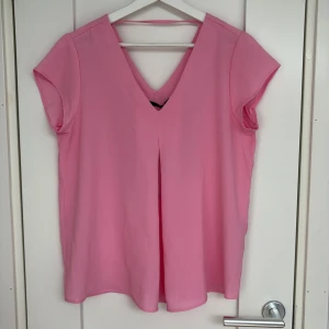 Rosa v-ringad blus från ONLY - Säljer en snygg rosa blus från ONLY i storlek 36. Blusen har v-ringning både fram och bak, korta ärmar och en lös passform. Perfekt för dig som gillar färg och vill ha en enkel men stilren topp i garderoben.