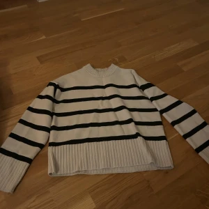 Randig stickad tröja från H&M XS - Säljer en vit stickad tröja från H&M i storlek XS med svarta horisontella ränder. Tröjan har ribbade muddar och nederkant samt rund halsringning. Perfekt för dig som gillar en klassisk och chill stil. Mycket bra skick 