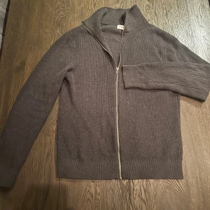 Grå cardigan zip storlek S - Säljer en stilren grå ribbad cardigan från East West storlek S med hel dragkedja framtill. Som nyskick! 