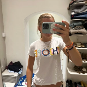 Stella McCartney tshirt  - Säljer en vit t-shirt med färgglad broderad HOPE-text framtill. T-shirten har rund hals och korta ärmar. Broderiet är i flera färger som blått, rosa, gult och orange, vilket ger en lekfull vibe. Perfekt för dig som gillar statement-plagg och vill ha något unikt i garderoben.