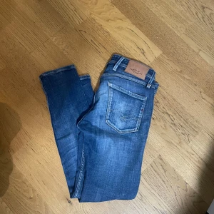 Replay Anbass slim fit jeans blå - Säljer ett par snygga Replay Anbass slim fit jeans i klassisk blå tvätt. Jeansen har fem fickor, läderpatch bak och diskreta slitningar för en cool look. Perfekta till sneakers eller boots och passar dig som gillar en smalare passform.