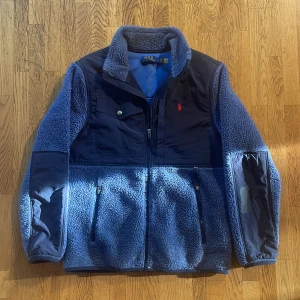 Blå fleecejacka från Polo Ralph Lauren - Säljer denna snygga blåa fleecejackan från Polo Ralph Lauren som passar perfekt nu till hösten!  Den har inga defekter alls! Priset är inte hugget i sten! Och hör av dig vid minsta fråga!