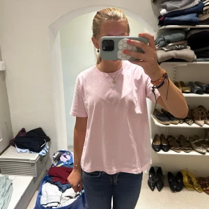 Ljusrosa t-shirt från Zara - Säljer en ljusrosa t-shirt från Zara med klassisk rund hals och korta ärmar. Modellen är enkel och loose fit, perfekt för en chill och avslappnad stil. Materialet är mjuk bomull som känns skönt mot huden. Passar dig som gillar basic och stilrena plagg.