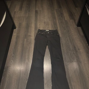 Svarta bootcut jeans - Svarta jeans från Gina tricot  i bootcut-modell med klassisk femficksdesign och snygga kopparfärgade nitar. Jeansen har normal passform och är tillverkade i stretchigt denim som sitter skönt. Perfekt för dig som gillar en tidlös look med lite extra edge.nyköpta så använda två gånger då dom är lite stora på mig så jag är tvungen att sälja dom. 
