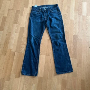 Levi's 527 bootcut jeans blå 33/34 - Snygga Levi's 527 jeans i klassisk blå denim med bootcut passform. Jeansen har fem fickor, gylf med dragkedja och tydliga kontrastsömmar. Perfekta för dig som gillar en tidlös look med lite utsvängda ben.