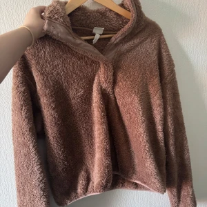 Brun fluffig fleece-tröja half zip - Supermjuk och mysig brun fleece-tröja med halv dragkedja i halsen. Perfekt för kyliga dagar och har en loose fit med långa ärmar. Den fluffiga ytan ger en riktigt cozy vibe och passar dig som gillar avslappnad stil.
