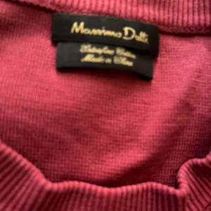Vinröd tröja från Massimo Dutti - Säljer en vinröd tröja från Massimo Dutti i enkel, klassisk modell med rund halsringning och ribbade muddar. Perfekt för dig som gillar stilrena plagg med en snygg färg. Materialet känns mjukt och bekvämt.
