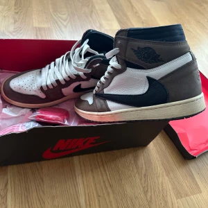 Nike Air Jordan 1 High OG Travis Scott - Nike Air Jordan 1 High OG Travis Scott i färgerna sail, svart och dark mocha. Skorna har dendär extra fickan som inte alla vet om. Kommer med extra skosnören. Släng ett bud har ingen aning vad de går för!