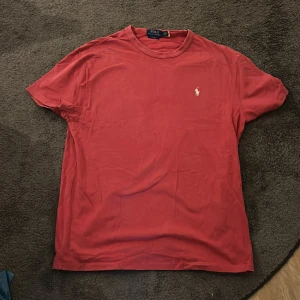 Röd t-shirt från Polo Ralph Lauren - Snygg röd t-shirt från Polo Ralph Lauren i Classic Fit. T-shirten har korta ärmar, rund hals och loggan på bröstet. Tillverkad i mjuk bomull. Priset kan diskuteras!!