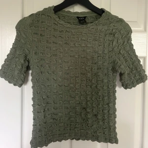 Grön ribbad topp från Lindex XS - Supersnygg grön topp från Lindex i storlek XS. Den har korta ärmar och ett ribbat, strukturerat tyg som ger en cool och unik look. Perfekt att styla med jeans eller kjol för en trendig outfit. Super snygg till hösten 💕