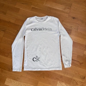 Vit långärmad tröja Calvin Klein - Vit långärmad tröja från Calvin Klein. En pytteliten fläck vid kraven som på bilden. Pris kan diskuteras. 