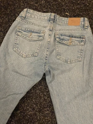 Ljusblå bootcut jeans - Snygga lågmidjade ljusblå jeans med bootcut med snygga detalger på fickorna.