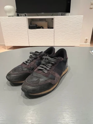 Valentino Rockrunner sneakers svart/vinröd - Snygga Valentino Rockrunner sneakers i svart och vinröd med coola detaljer och platt sula. Skorna har snörning, rund tå och en mix av mocka och skinn. Bakpartiet har nitar och kontrasterande färg. Perfekta för dig som gillar exklusiva sneakers med edge.