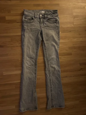 Grå lowrise bootcut jeans - Gråa, lowwaist, bootcut jeans från Gina Tricot! Midjemått: 34cm, passar mig som är 172cm i längd men kan nog passa lite längre och kortare också!