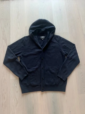 Mörkblå hoodie-kofta från Less Worries - Mörkblå hoodie-kofta från Less Worries med huva och knappar framtill. Nyskick och går för 1800 ny.