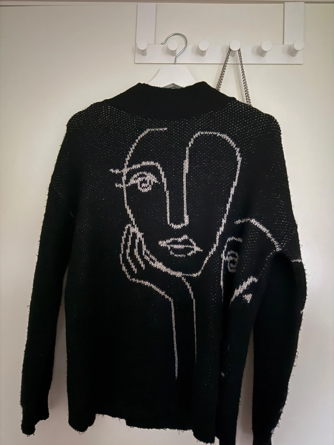 Svart stickad tröja med ansiktsmotiv