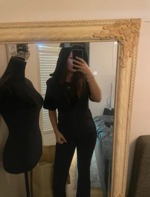 Svart Zara väst - Säljer en svart Zara väst med stor huva och dragkedja framtill. Jackan har en snygg, figurnära passform och är perfekt för lager på lager.