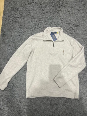 Ralph Lauren Half-Zip - Helt ny och oanvänd Ralph Lauren half-zip, 10/10 skick. Det är mycket i ljus i bilderna, så tröjan är lite mer beige i verkligheten, men inte så stor skillnad. Det är storlek L men jag skulle säga att den även passar M. Riktigt stilig och bekväm, rekommenderar starkt!