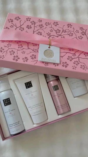 Rituals The Ritual of Sakura presentbox - Lyxig presentbox från Rituals med serien The Ritual of Sakura. Innehåller duschgel, body cream, body lotion mousse och ett doftljus. Produkterna har en fräsch doft av ris och körsbärsblom. Kommer i en söt rosa ask med blommönster och rosett.