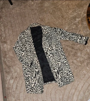 Leopardmönstrad kappa från Zara Woman - Säljer en snygg leopardmönstrad kappa från Zara Woman. Jackan är svart och beige med klassisk krage, helknäppning och helsvart foder. Perfekt statement-plagg för dig som vill sticka ut och addera lite edge till din outfit.