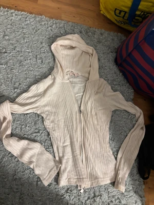 Ljusbeige ribbad hoodie från Nelly - Säljer en ljusbeige hoodie från Nelly i storlek XS. Tröjan är ribbad, har dragkedja framtill och en skön huva. Materialet känns mjukt och lätt, perfekt för chill dagar. Långärmad och med slim passform som sitter snyggt.💛💛