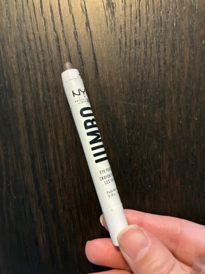 NYX Jumbo ögonpenna brun - NYX Jumbo Eye Pencil i en mjuk brun nyans. Pennan har en krämig formula som är enkel att sudda ut och funkar både som ögonskugga och eyeliner. Höljet är vitt med svart text och genomskinligt lock. Perfekt för snabba sminkningar och kreativa looks. Endast testad ca 2 ggr. 