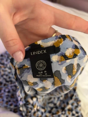 Leopardmönstrad långkjol från Lindex - Säljer en flowy långkjol från Lindex med blått, svart, vitt och senapsgult leopardmönster. Kjolen har en mjuk och lätt känsla, perfekt för dig som gillar statementplagg. Midjemodell och snyggt fall.