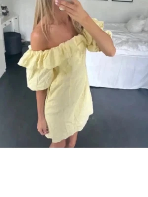 Gul offshoulder klänning med volang - Söt ljusgul kortklänning med offshoulder och puffiga ärmar. Klänningen har en bred volang runt axlarna och är tillverkad i ett lätt linneliknande material. Perfekt för sommarens alla tillfällen och ger en romantisk vibe. Strl 44 men passar mig som vanligtvis har S