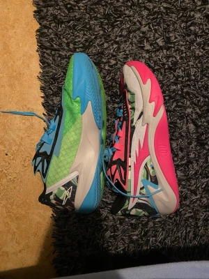 Färgglada sneakers med blå och rosa detaljer - Unika sneakers med asfeta färgblock i blått, grönt och rosa. Ena skon är grön/blå och den andra rosa/blå, båda med svarta och vita grafiska detaljer samt blå skosnören. Snygg vågig design på sidorna och coola mönster på sulan. Perfekta för dig som vill sticka ut.